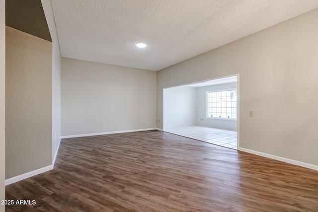 spare room with baseboards, wood finished floors, a textured ceiling, and recessed lighting