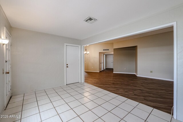 empty room featuring baseboards, light wood finished floors, and visible vents