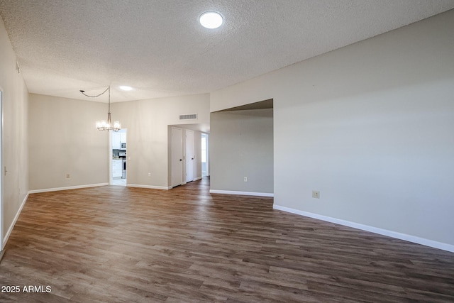 interior space featuring an inviting chandelier, visible vents, baseboards, a textured ceiling, and dark wood-style flooring