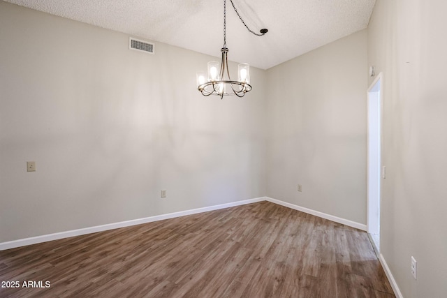 unfurnished dining area featuring a chandelier, wood finished floors, visible vents, and baseboards