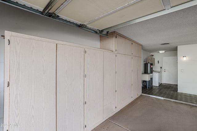 garage with visible vents, water heater, and washer / clothes dryer