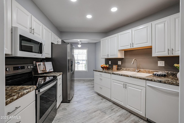 kitchen featuring white cabinets, a sink, white appliances, and recessed lighting