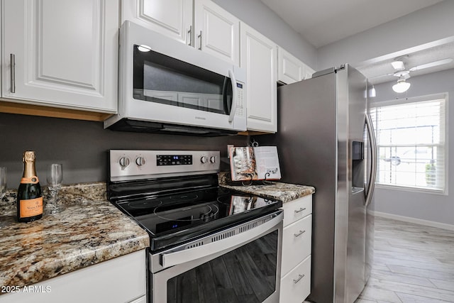 kitchen featuring light stone counters, white cabinetry, light wood-style flooring, baseboards, and appliances with stainless steel finishes