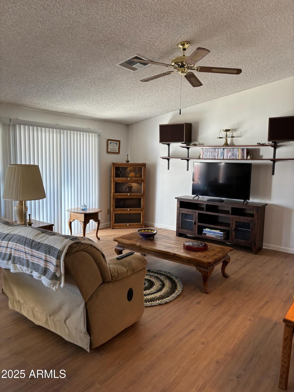 living room featuring lofted ceiling, ceiling fan, hardwood / wood-style flooring, and a textured ceiling