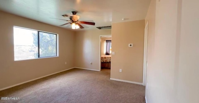 carpeted spare room featuring baseboards and ceiling fan