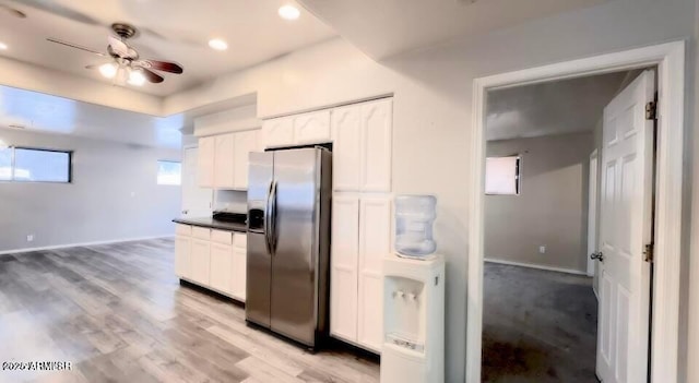 kitchen with dark countertops, white cabinets, stainless steel fridge with ice dispenser, and light wood-style flooring