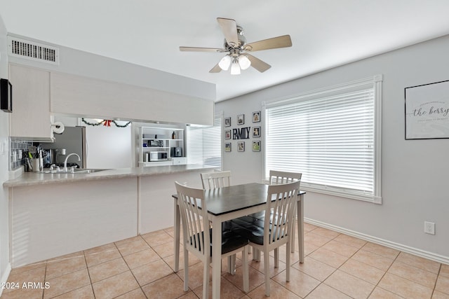 tiled dining area with ceiling fan and sink