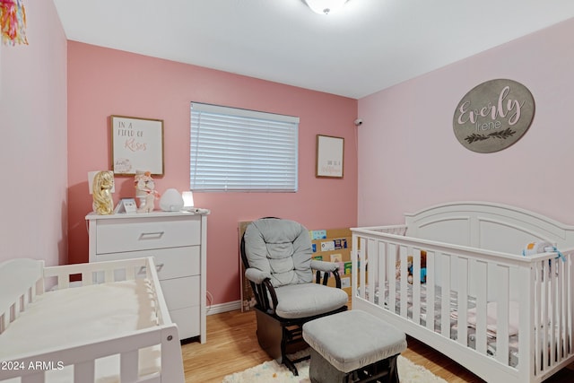 bedroom featuring a crib and light hardwood / wood-style flooring