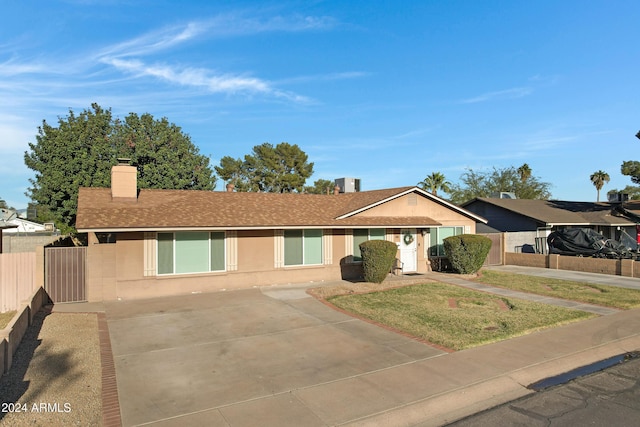 ranch-style house featuring a front yard and central AC unit