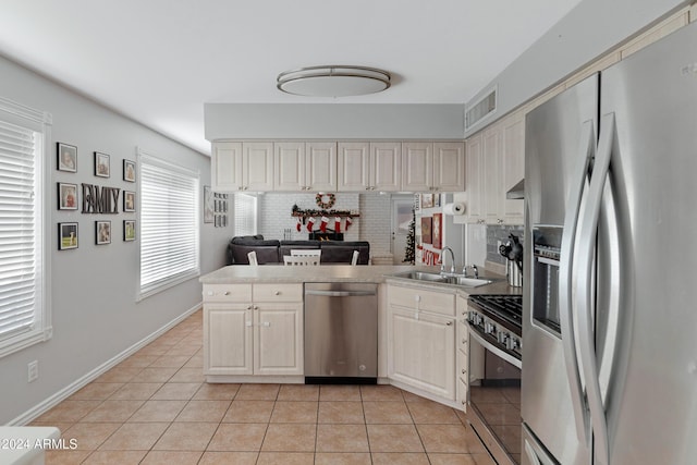 kitchen with backsplash, sink, light tile patterned flooring, and stainless steel appliances