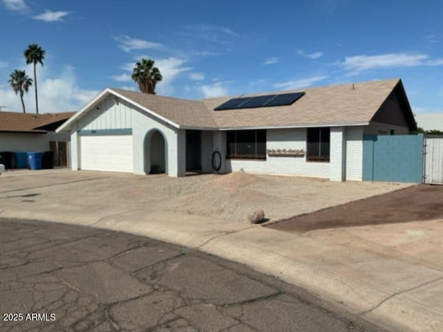 single story home with a gate, fence, driveway, a garage, and solar panels
