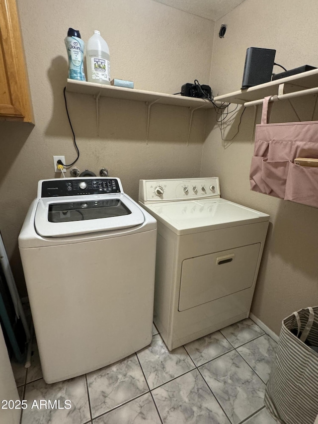 laundry room featuring washing machine and dryer, cabinet space, and marble finish floor