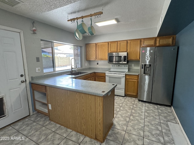 kitchen featuring a sink, a peninsula, stainless steel appliances, visible vents, and light countertops