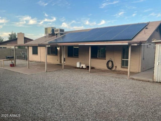 back of house featuring a patio area and solar panels
