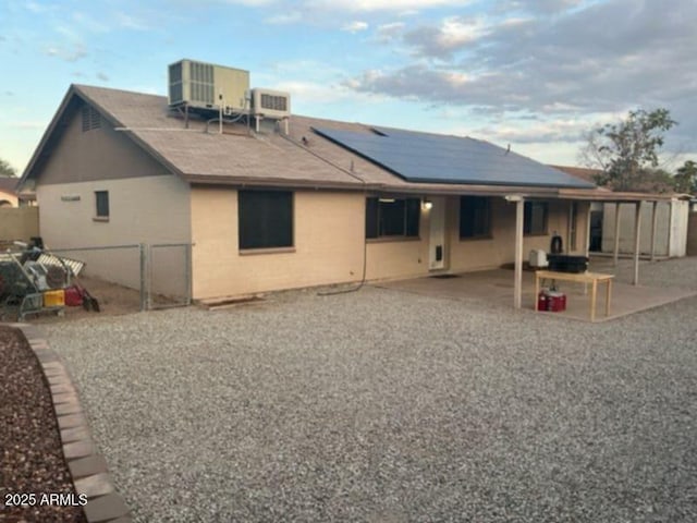back of property with cooling unit, a patio, solar panels, and a fenced backyard