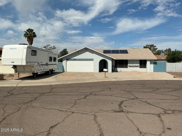 view of front of home featuring roof mounted solar panels, fence, and concrete driveway