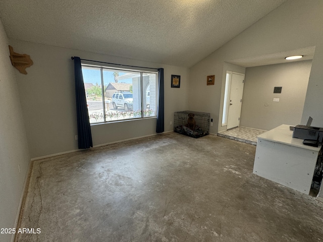unfurnished living room with vaulted ceiling, a textured ceiling, and concrete flooring