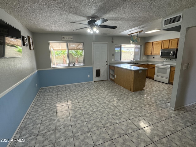 kitchen featuring ceiling fan, visible vents, stainless steel microwave, white range with electric cooktop, and a peninsula