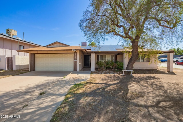 single story home featuring driveway, a garage, and roof mounted solar panels