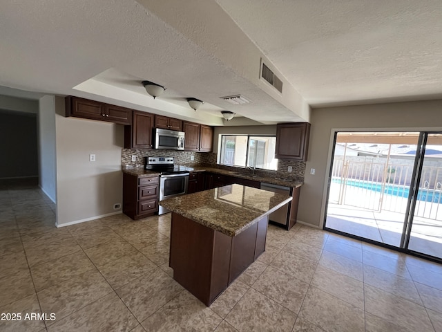 662 W Laguna Azul Ave, Mesa, AZ 85210 - kitchen featuring stainless steel appliances, a textured ceiling, decorative backsplash, a kitchen island, and dark brown cabinetry