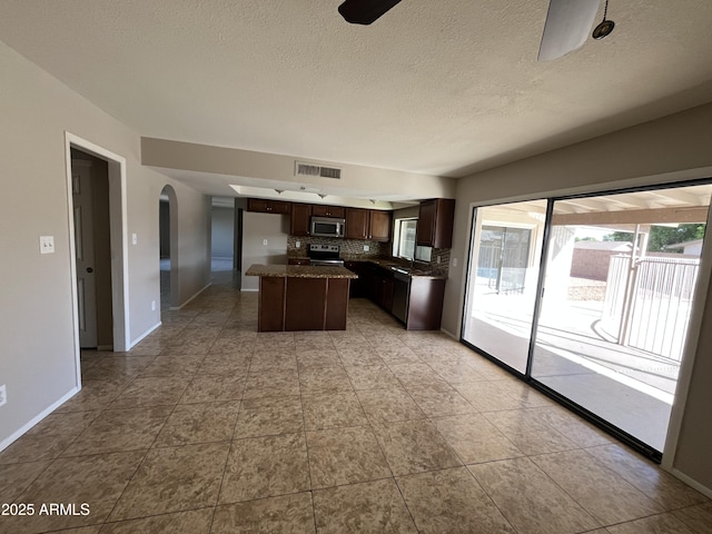 662 W Laguna Azul Ave, Mesa, AZ 85210 - kitchen featuring appliances with stainless steel finishes, tasteful backsplash, arched walkways, a kitchen island, and dark brown cabinets