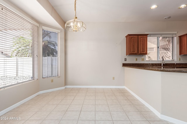 unfurnished dining area featuring an inviting chandelier and light tile patterned floors