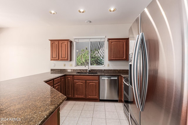 kitchen with light tile patterned flooring, appliances with stainless steel finishes, sink, and dark stone counters