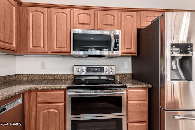 kitchen with dark stone countertops and stainless steel appliances