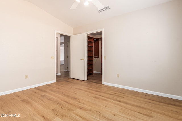 unfurnished bedroom with ceiling fan, light hardwood / wood-style flooring, a walk in closet, and a closet