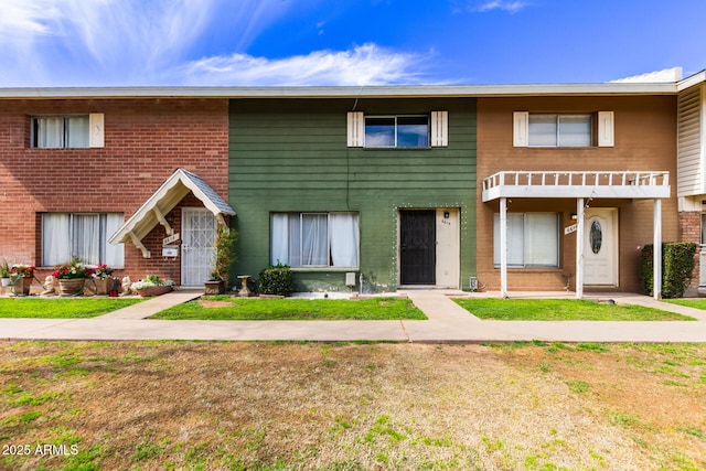 view of property featuring brick siding and a front lawn