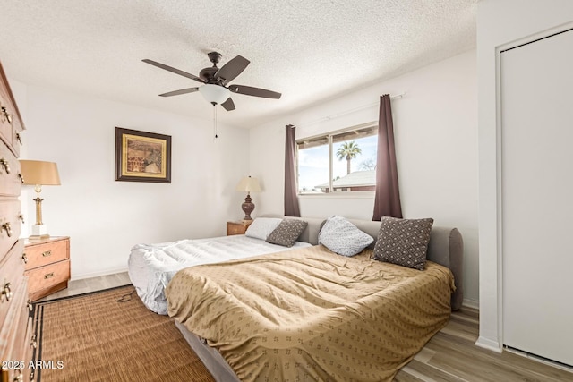 bedroom featuring a textured ceiling, a ceiling fan, and wood finished floors