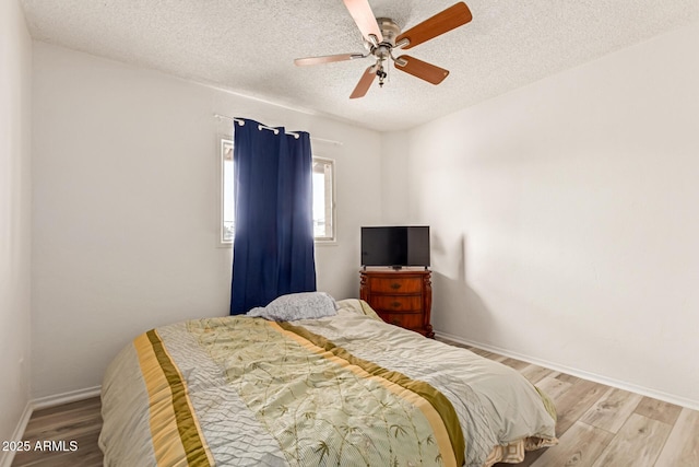 bedroom with a ceiling fan, a textured ceiling, baseboards, and wood finished floors