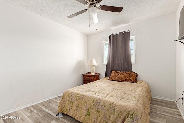 bedroom with a textured ceiling, ceiling fan, baseboards, and light wood-style floors