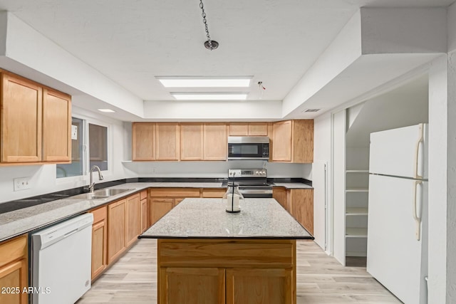 kitchen featuring light wood-style flooring, a kitchen island, appliances with stainless steel finishes, and a sink