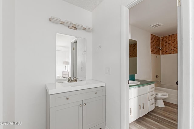 full bath with toilet, wood finished floors, vanity, visible vents, and shower / bathing tub combination