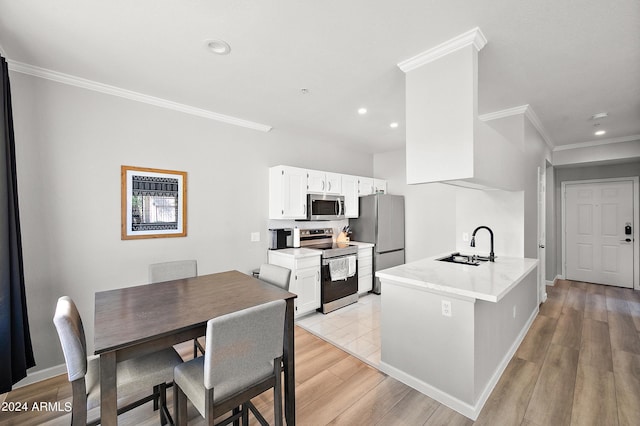 kitchen featuring stainless steel appliances, light countertops, light wood-style floors, white cabinetry, and a sink