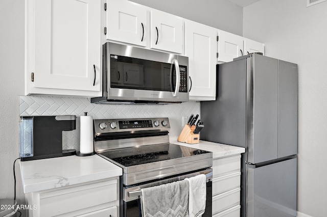 kitchen featuring stainless steel appliances, backsplash, and white cabinetry