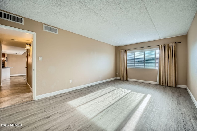 spare room featuring light hardwood / wood-style floors and a textured ceiling