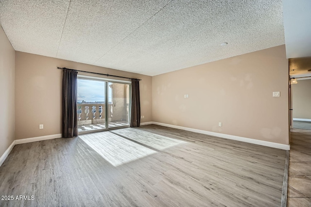 unfurnished room featuring wood-type flooring and a textured ceiling