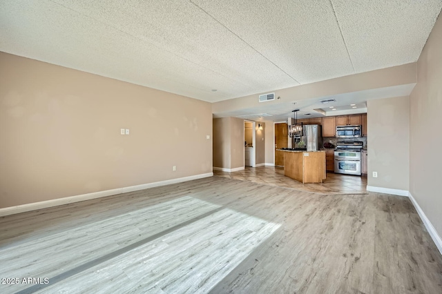 unfurnished living room featuring a textured ceiling and light hardwood / wood-style floors