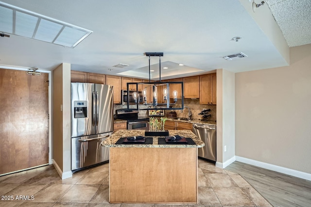 kitchen with appliances with stainless steel finishes, decorative light fixtures, sink, a center island, and a raised ceiling