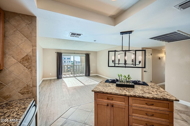 kitchen featuring light tile patterned floors, decorative light fixtures, and dark stone counters