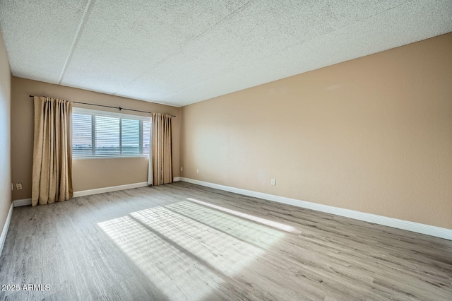 empty room featuring a textured ceiling and light hardwood / wood-style floors