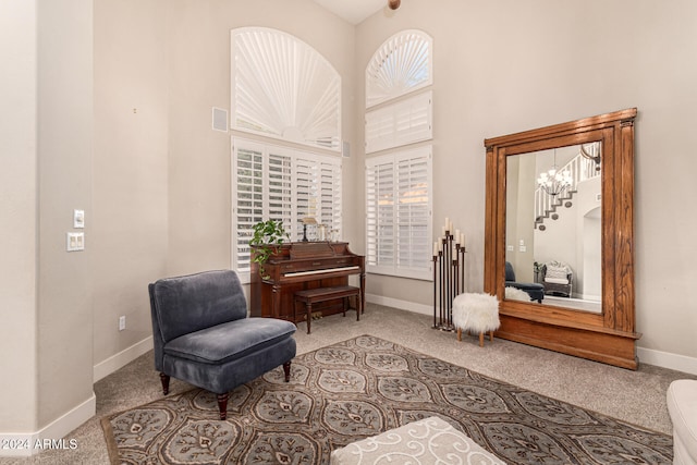 living area with a high ceiling and light colored carpet