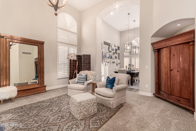 living area with a high ceiling, light carpet, and a notable chandelier