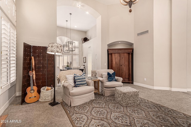 sitting room featuring a notable chandelier, a high ceiling, and carpet flooring