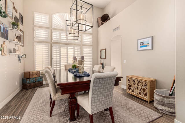 dining space featuring a high ceiling, dark hardwood / wood-style floors, and a notable chandelier