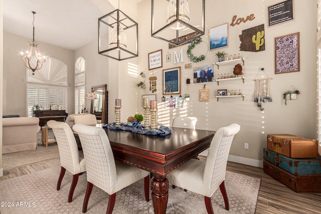 dining room featuring wood-type flooring, a high ceiling, and a notable chandelier