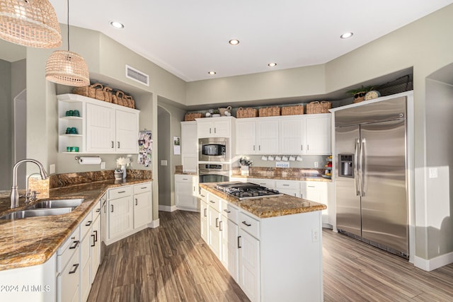 kitchen featuring sink, pendant lighting, dark stone counters, and built in appliances