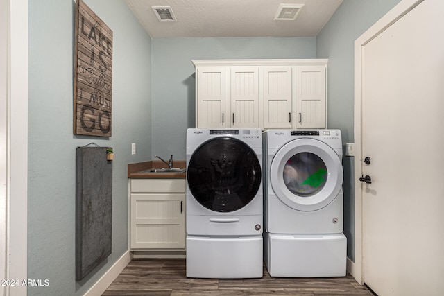 washroom featuring dark wood-type flooring, cabinets, separate washer and dryer, and sink